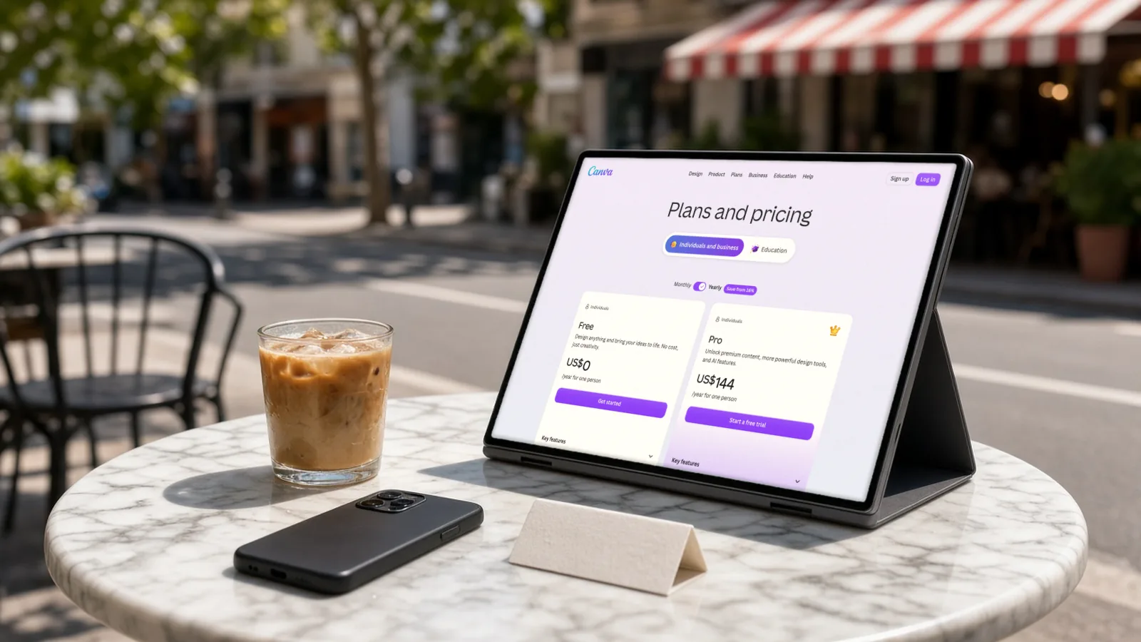 Tablet on a cafe table in midday sun showing Canva's Free and Pro plan prices