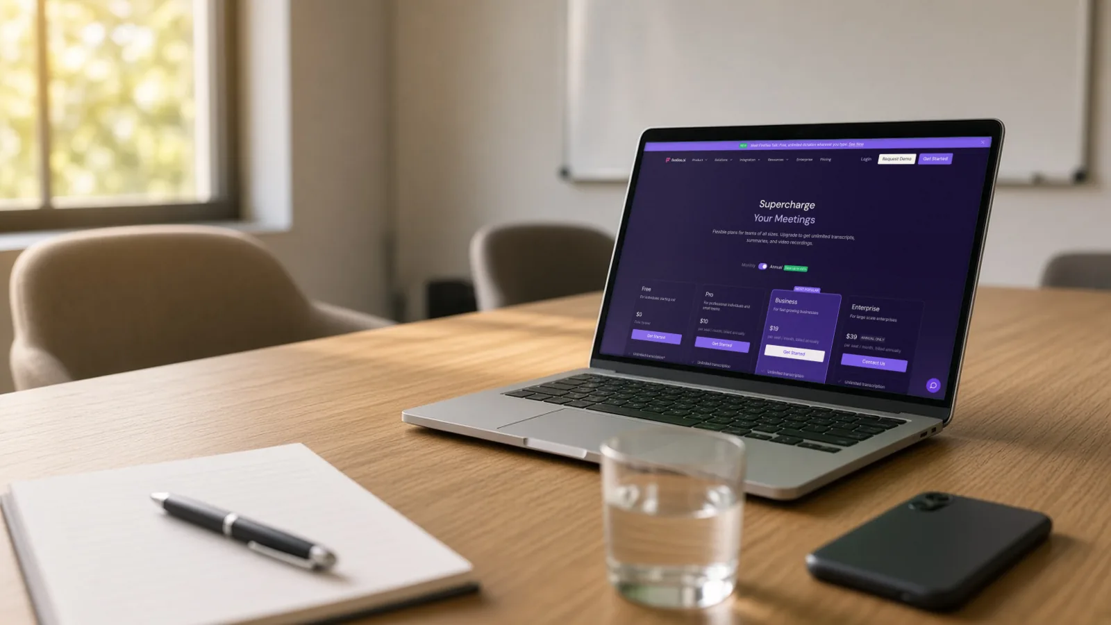 Laptop on a meeting-room table showing the official Fireflies.ai pricing page